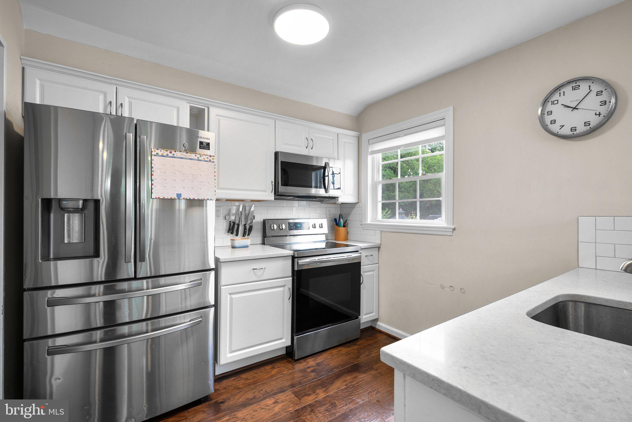 12837 Flack Street Silver Spring, MD 20906 - Photo 8 of 26 a kitchen with stainless steel appliances granite countertop a refrigerator a stove a sink and a microwave