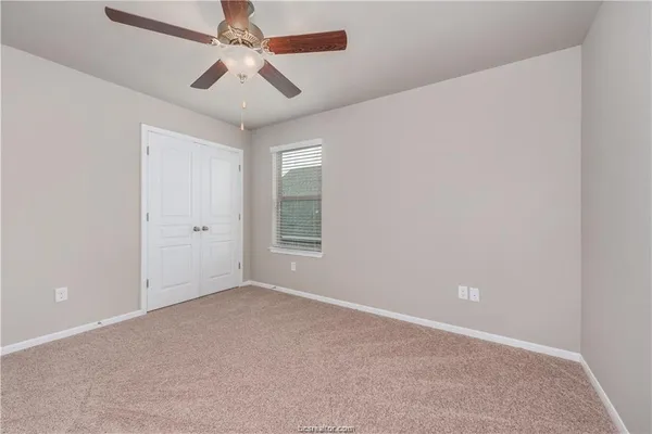 an empty room with a window and a fan