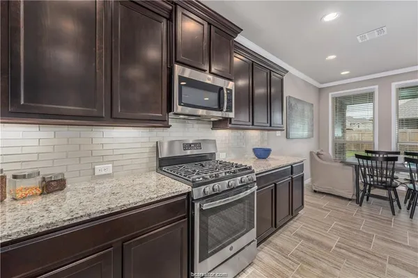 a kitchen with stainless steel appliances granite countertop a stove a sink and a microwave