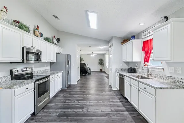 a large kitchen with stainless steel appliances lots of counter space sink and window