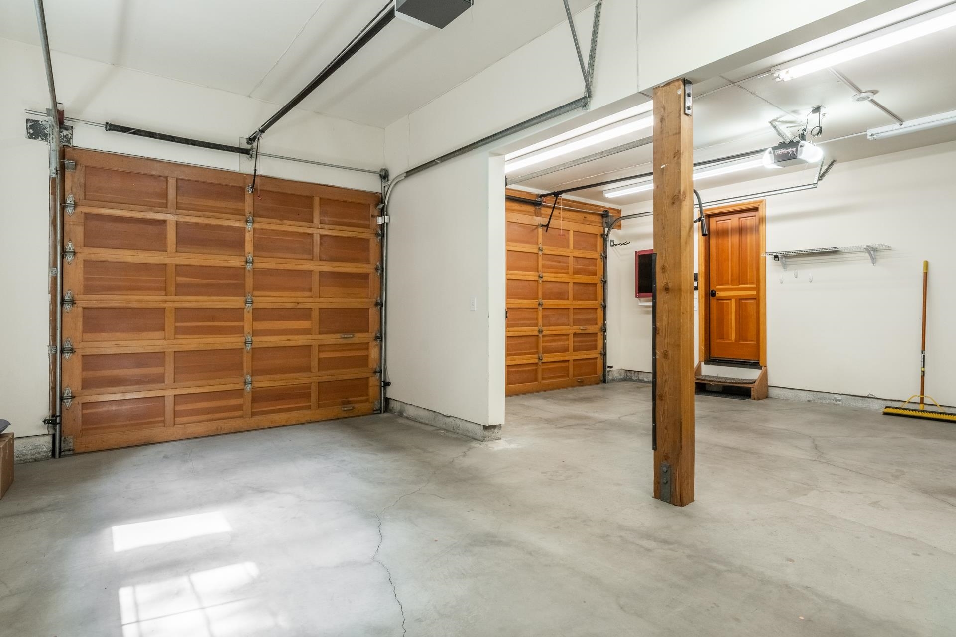 272 Ridge Way Mammoth Lakes, CA 93546 - Photo 46 of 55 Multi-bay garage featuring two wood-panel garage doors, concrete flooring, and overhead fluorescent lighting
