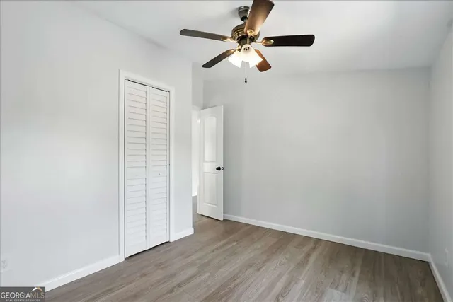 an empty room with wooden floor fan and windows