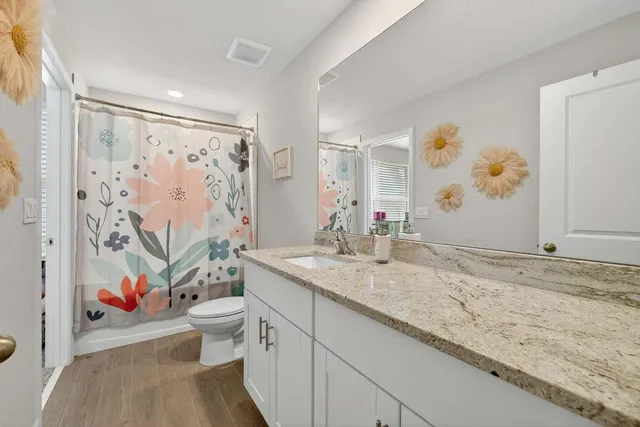 a bathroom with a granite countertop sink mirror vanity and toilet