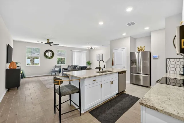 a kitchen with a sink a refrigerator and chairs
