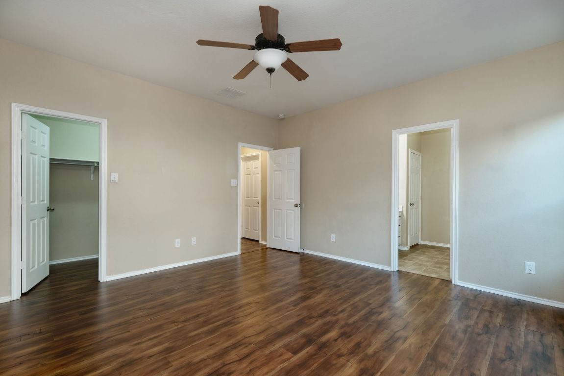 1244 Yellow Iris Road Leander, TX 78641 - Photo 12 of 25 an empty room with wooden floor ceiling fan and windows