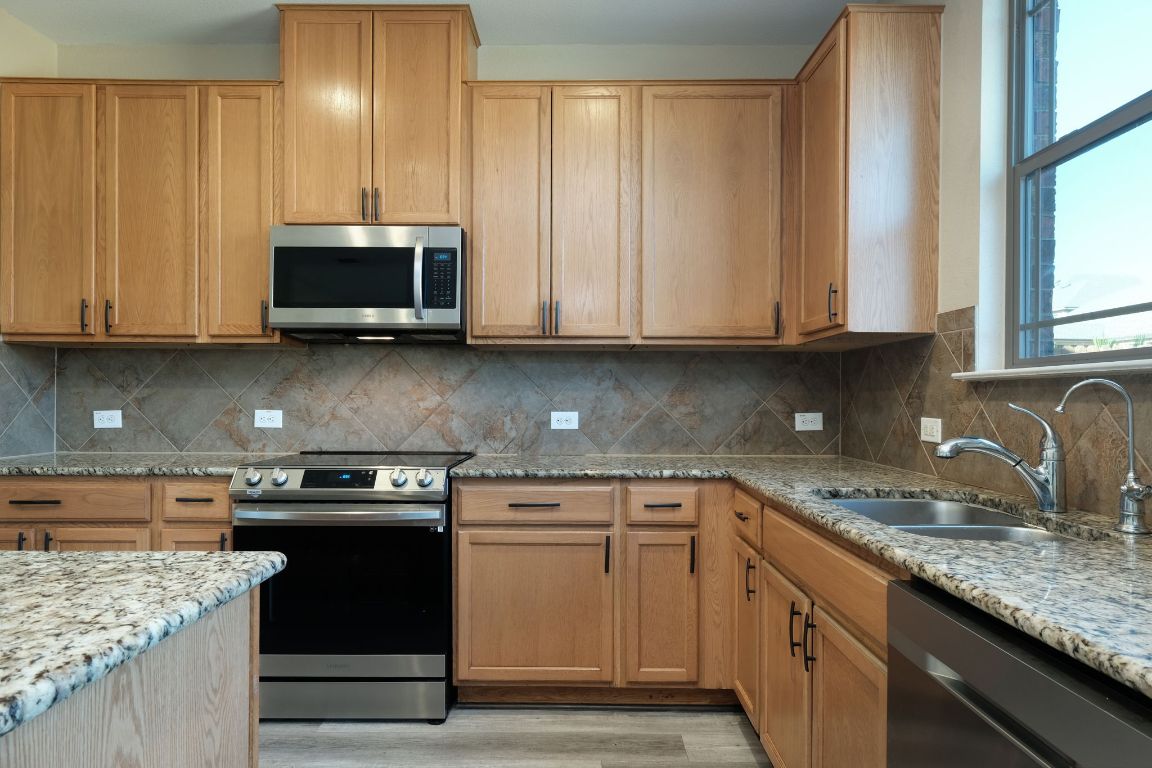 1244 Yellow Iris Road Leander, TX 78641 - Photo 9 of 25 a kitchen with stainless steel appliances granite countertop a sink stove and microwave