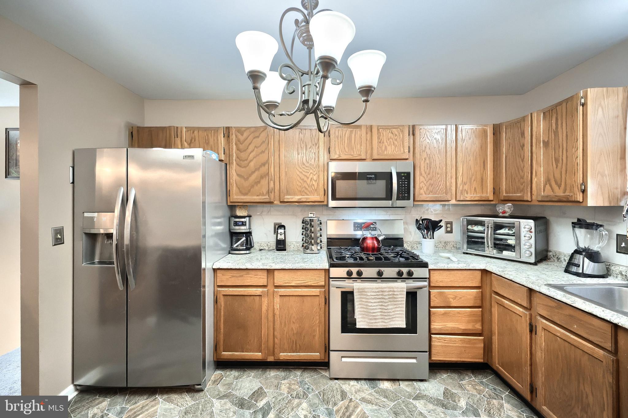 225 Edinburgh Road York, PA 17406 - Photo 7 of 40 a kitchen with stainless steel appliances granite countertop a refrigerator a stove a sink and dishwasher with white cabinets