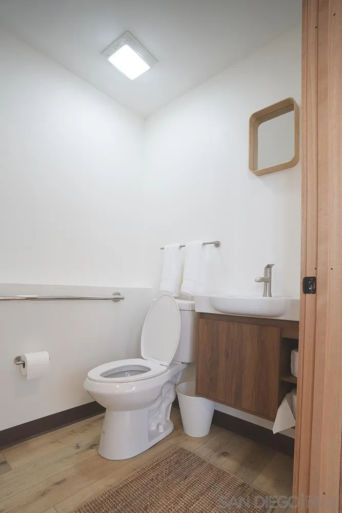 5065 Waterview Way, Unit 101 Oceanside, CA 92057 - Photo 14 of 19 a white toilet sitting next to a bathroom sink and vanity