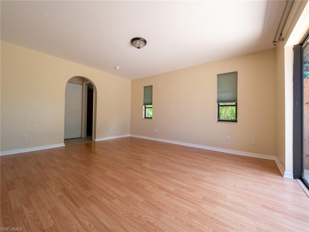 18414 Tulip Road Fort Myers, FL 33967 - Photo 18 of 37 Spacious room featuring wood-finish flooring, an arched doorway, and multiple windows with roller shades