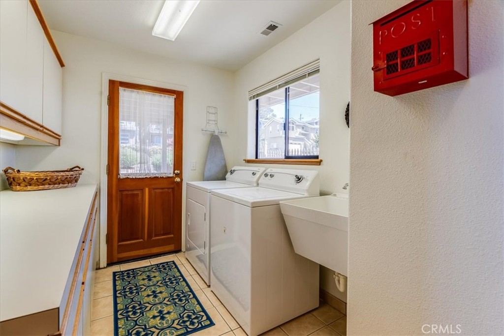 390 Lampton Street Cambria, CA 93428 - Photo 50 of 68 The large laundry room has a plethora of cabinetry, sink, and a door to the exterior yard space.