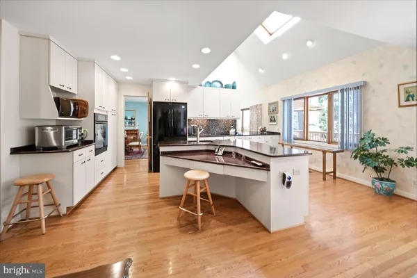 a kitchen with stainless steel appliances kitchen island granite countertop a stove top oven a sink a dining table and chairs