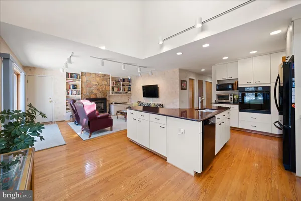 a large white kitchen with stainless steel appliances granite countertop a stove and a wooden floors