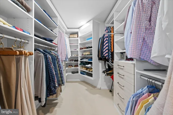 a view of walk in closet with clothes and shoes