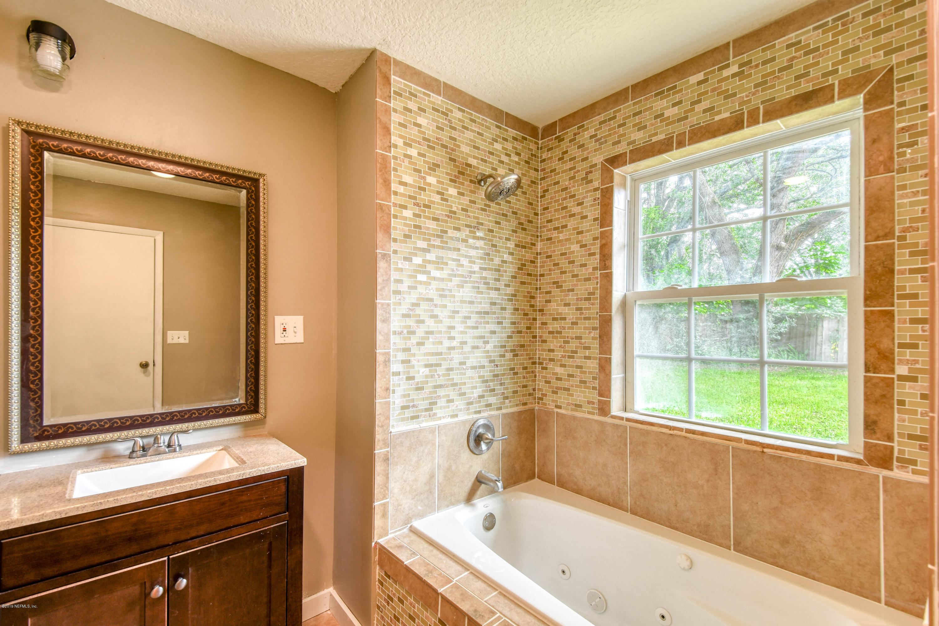4623 Martingale Road Jacksonville, FL 32210 - Photo 11 of 18 a bathroom with a tub sink and mirror