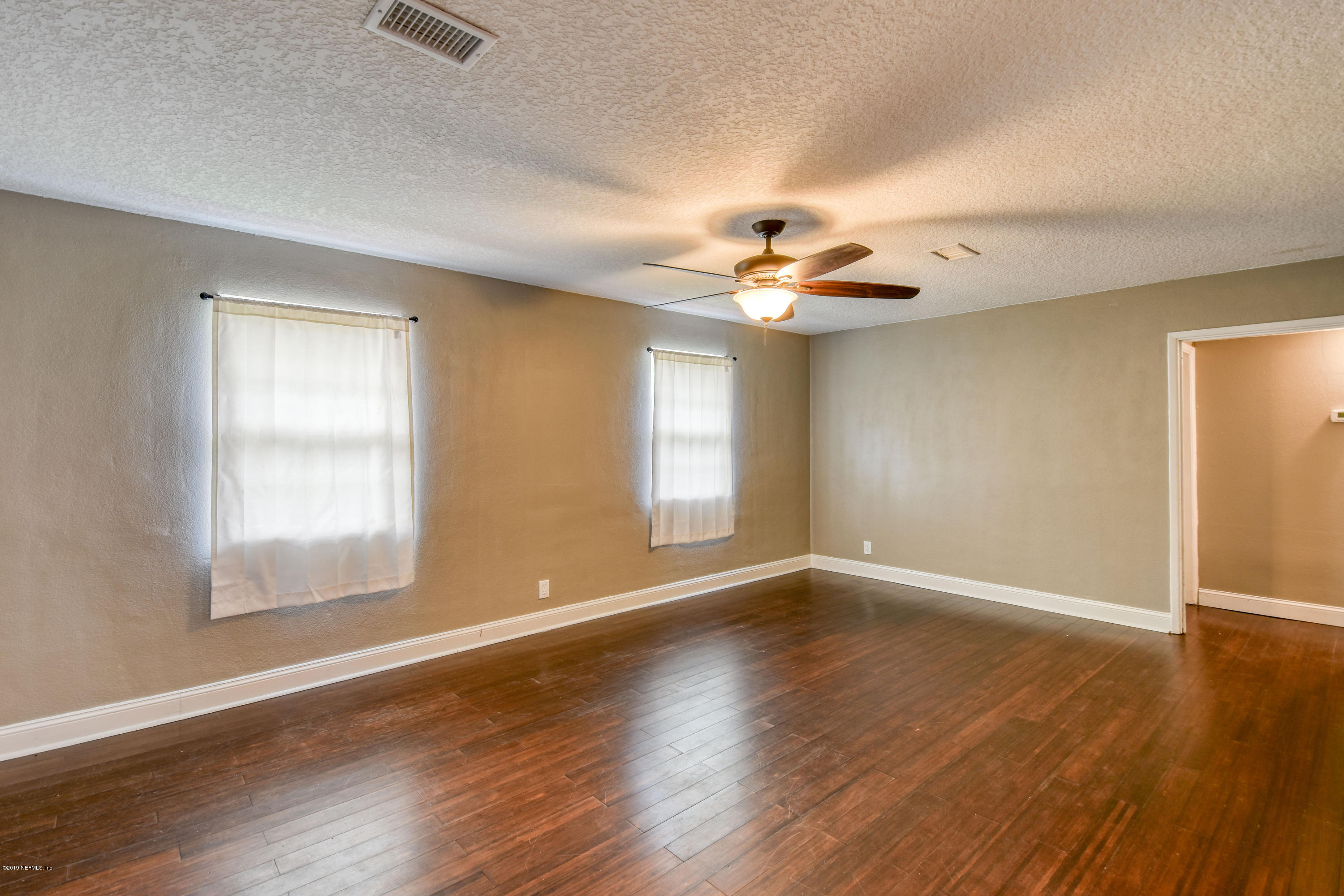 4623 Martingale Road Jacksonville, FL 32210 - Photo 2 of 18 an empty room with wooden floor chandelier fan and windows