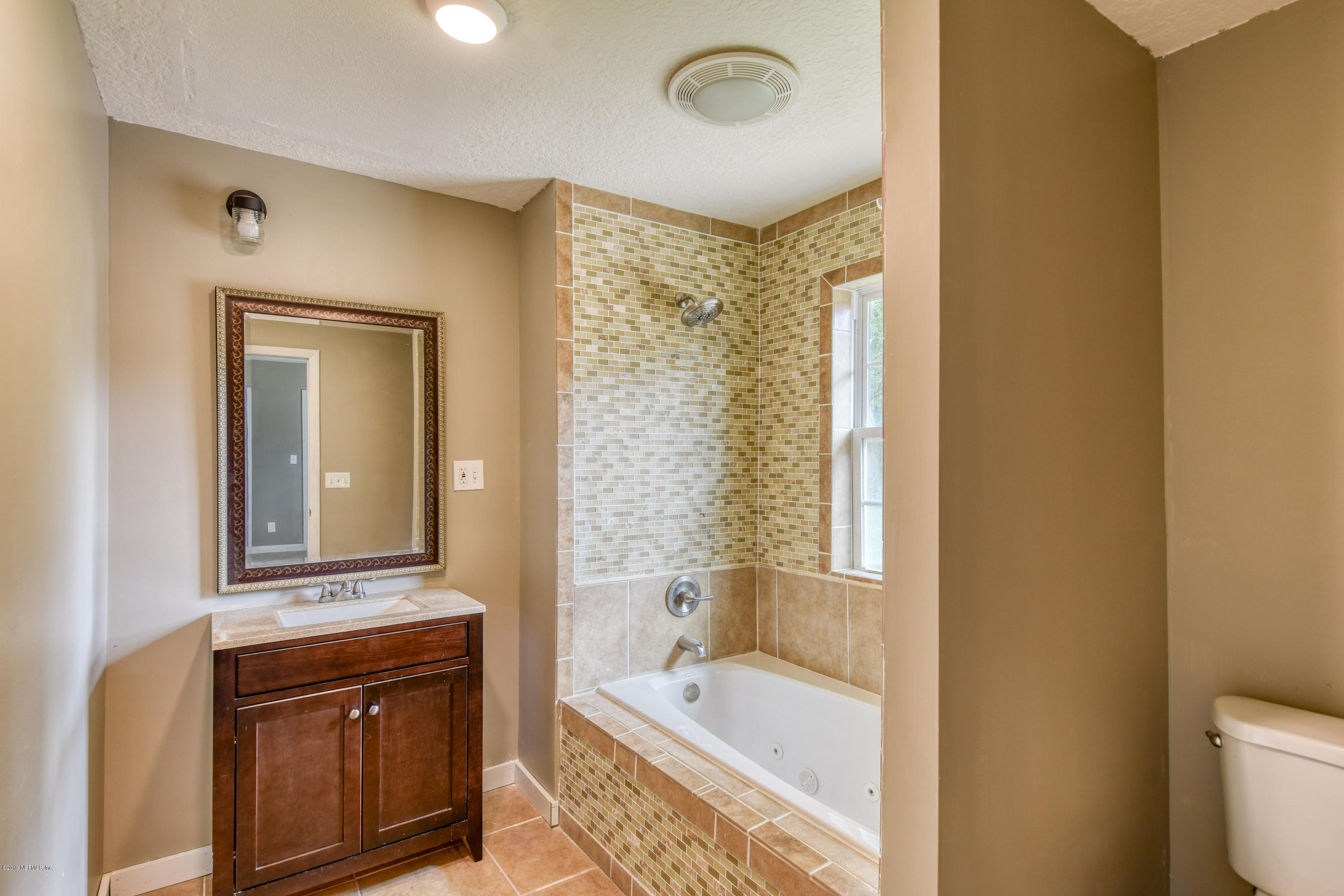 4623 Martingale Road Jacksonville, FL 32210 - Photo 10 of 18 a bathroom with a tub sink and mirror