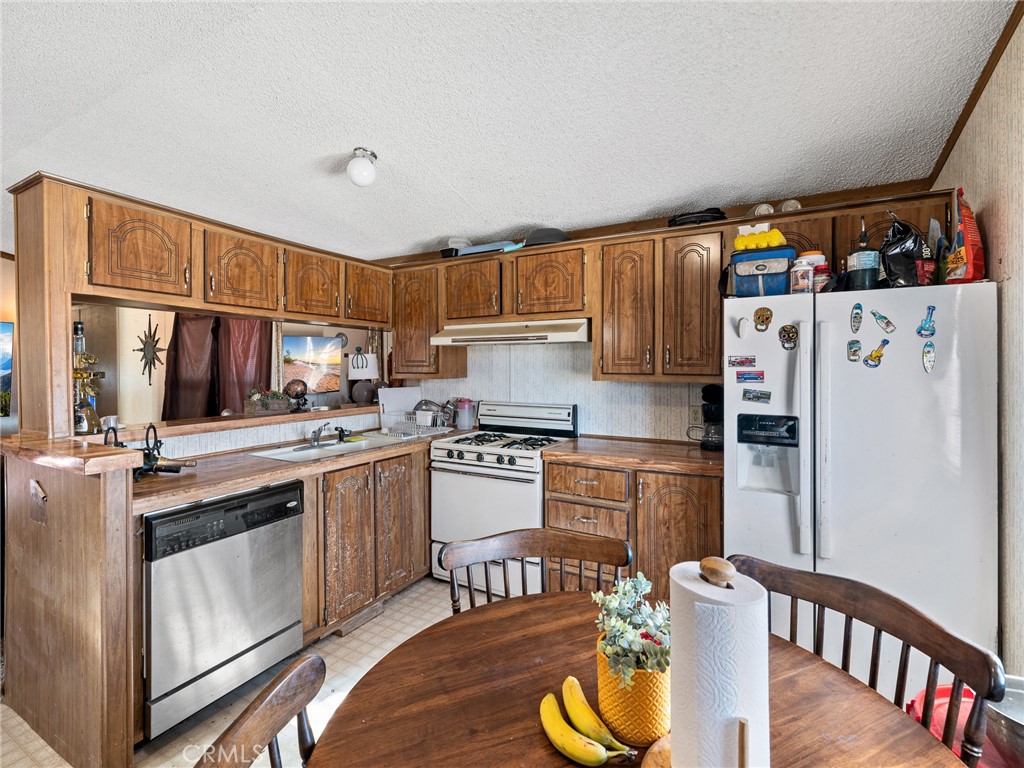 39626 East End Road Lucerne Valley, CA 92356 - Photo 3 of 29 a kitchen with a refrigerator a stove a sink dishwasher and wooden cabinets with wooden floor