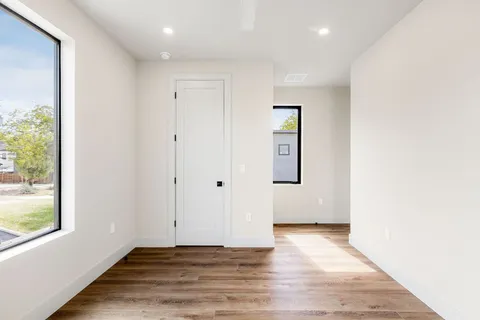 an empty room with wooden floor and windows