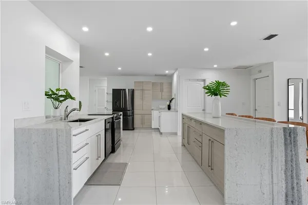 a large kitchen with stainless steel appliances a large counter top a sink and a stove