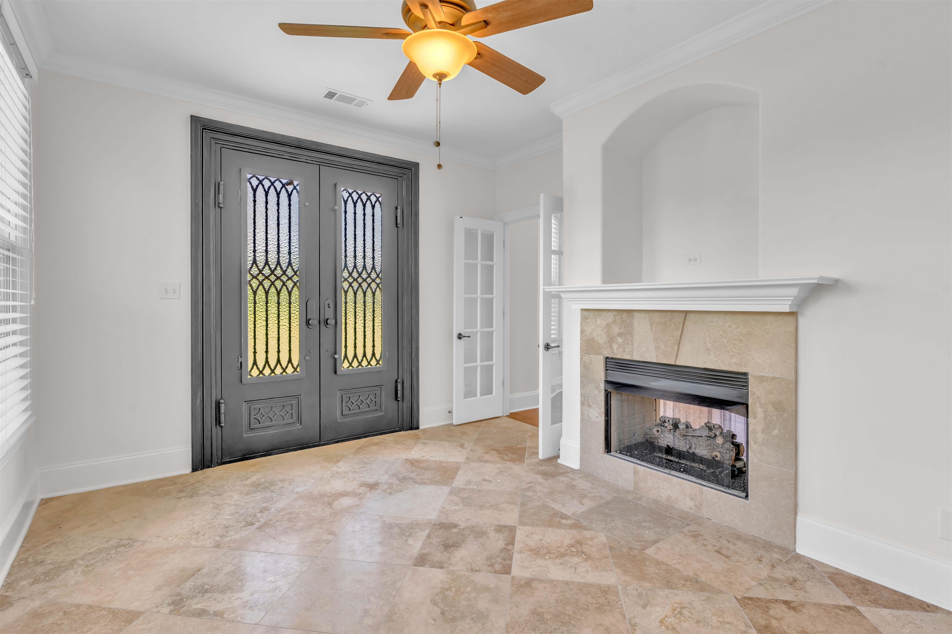 680 Highway 193 Collierville, TN 38017 - Photo 16 of 38 Decorative double entry doors with intricate glass and ironwork, complemented by a corner fireplace featuring a stone surround and mantle