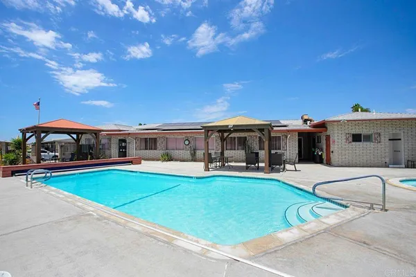 a view of a swimming pool with lawn chairs under an umbrella