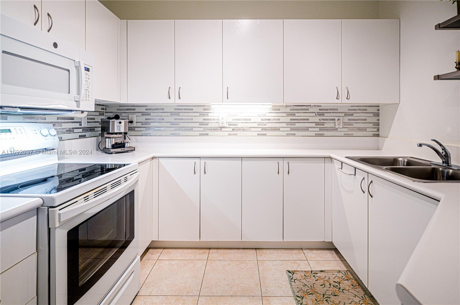 75 Gulfstream Road, Unit 107B Dania Beach, FL 33004 - Photo 19 of 71 a kitchen with granite countertop white cabinets and white appliances