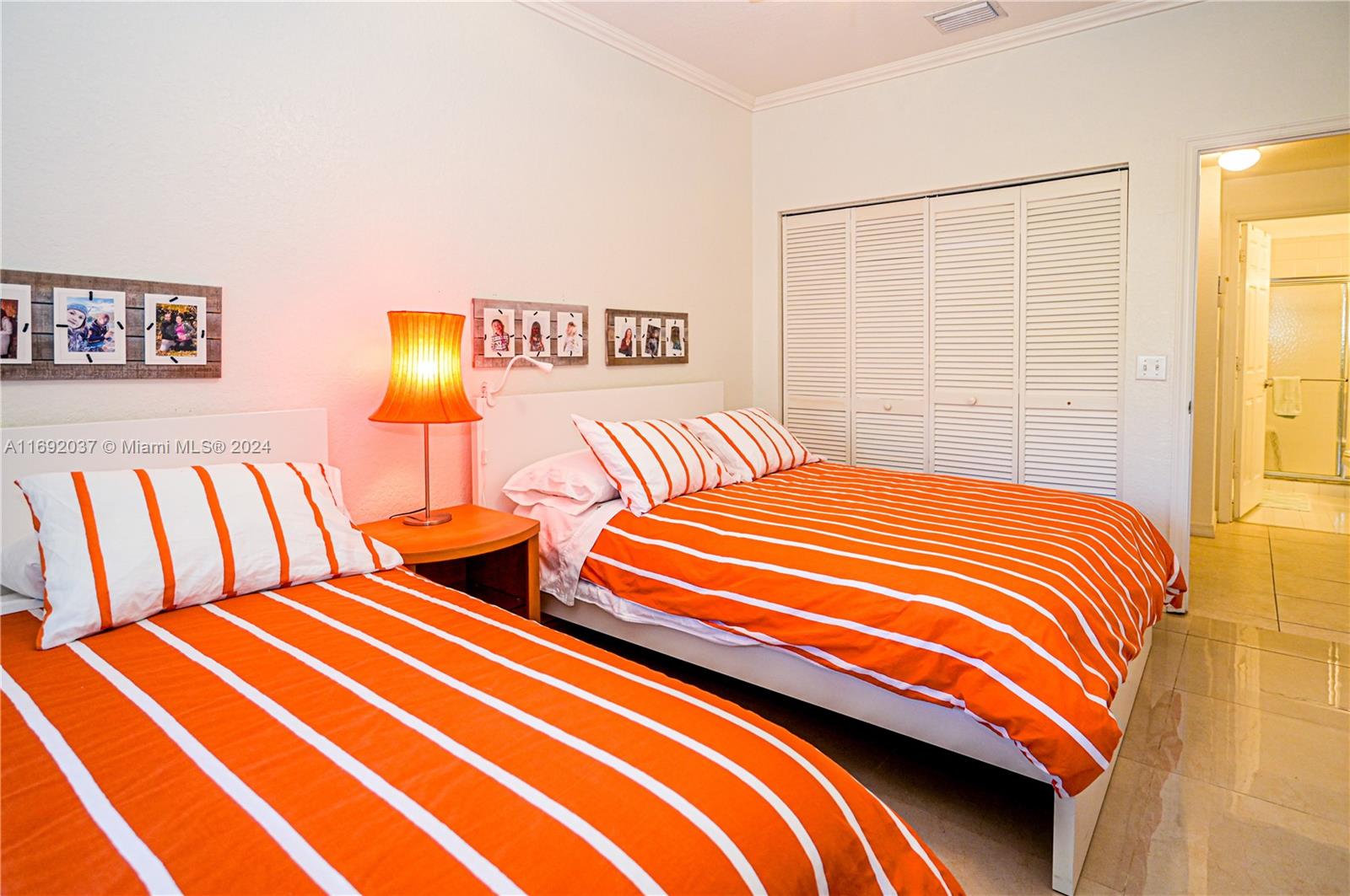 75 Gulfstream Road, Unit 107B Dania Beach, FL 33004 - Photo 36 of 71 a bedroom with two beds and a lamp next to a window