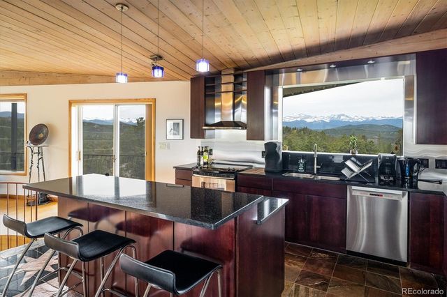 a kitchen with stainless steel appliances kitchen island granite countertop a refrigerator a sink a stove and wooden cabinets