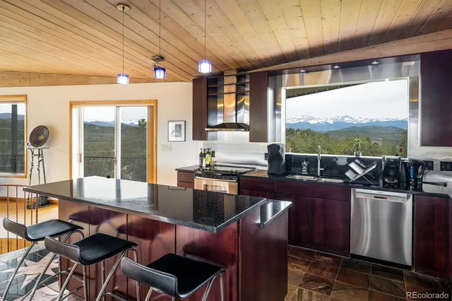 a kitchen with stainless steel appliances kitchen island granite countertop a refrigerator a sink a stove and wooden cabinets