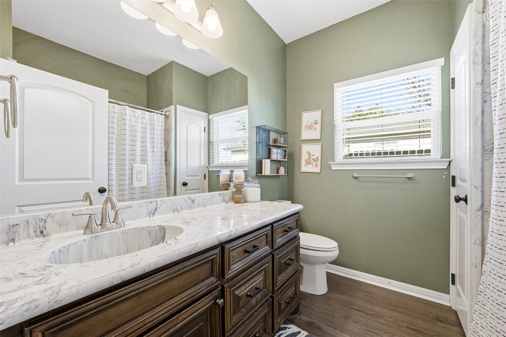 12992 Old Dallas Road West, TX 76691 - Photo 18 of 25 a bathroom with a granite countertop sink a toilet and a large mirror