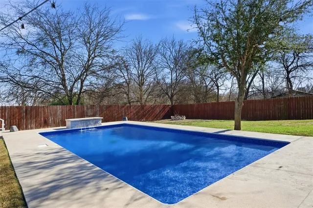 a view of pool with yard and wooden fence