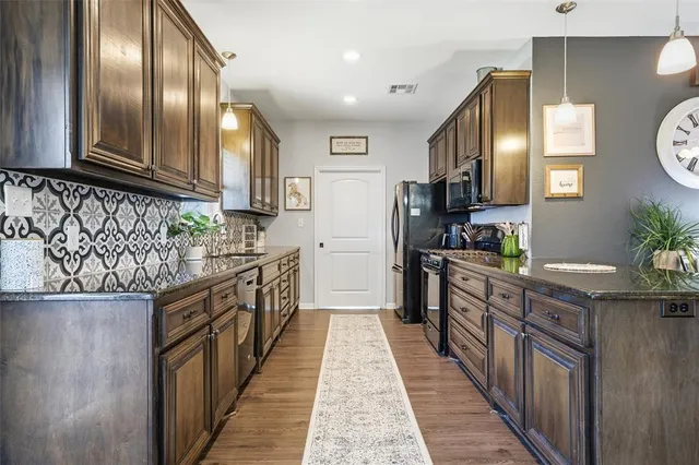 a kitchen with stainless steel appliances granite countertop lots of counter top space and wooden floor