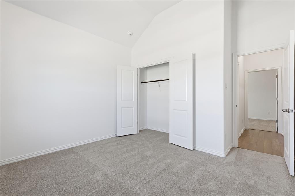 2529 Rivers W Road Anna, TX 75409 - Photo 4 of 40 Spacious interior room featuring light gray carpeting, white baseboards, and a white interior door with a paneled design