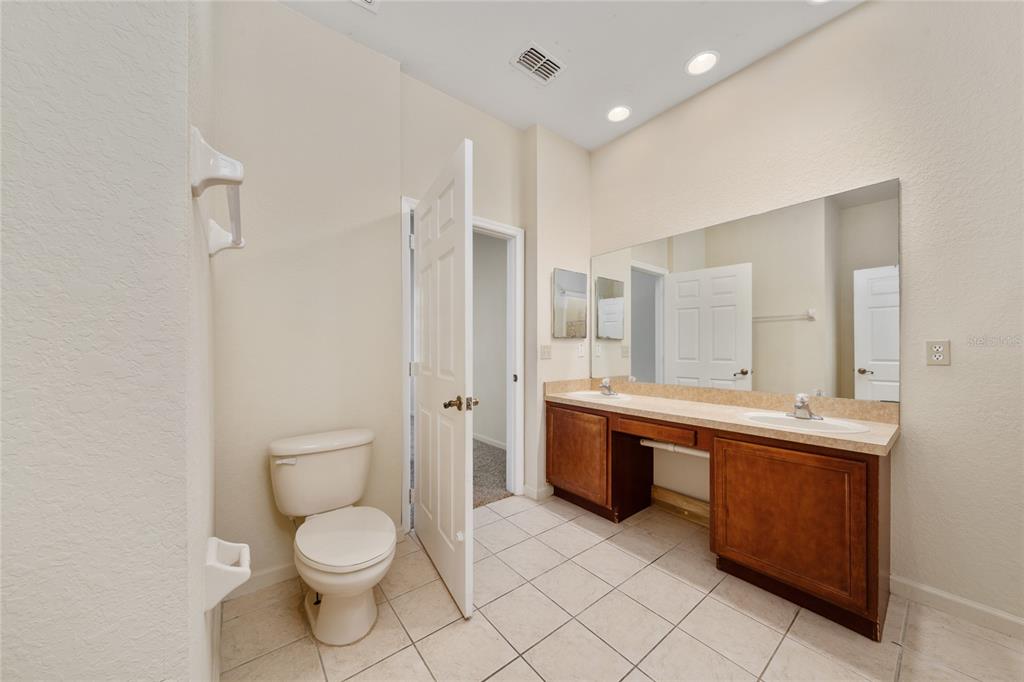3001 Greystone Loop, Unit 103 Kissimmee, FL 34741 - Photo 16 of 31 a spacious bathroom with a granite countertop toilet sink and mirror