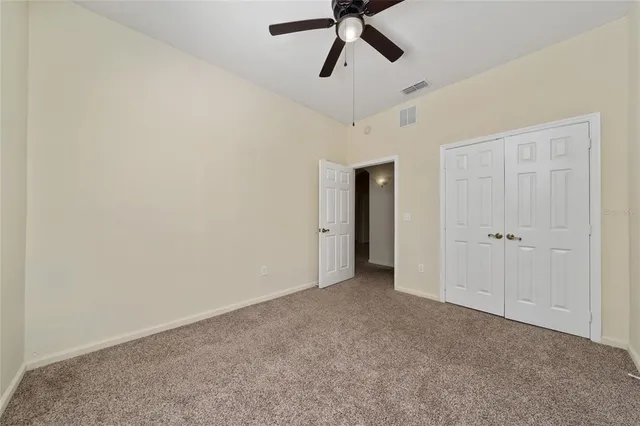 a view of an empty room and chandelier fan