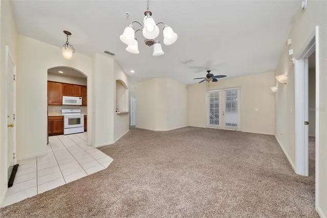 a view of a livingroom with a chandelier fan and windows