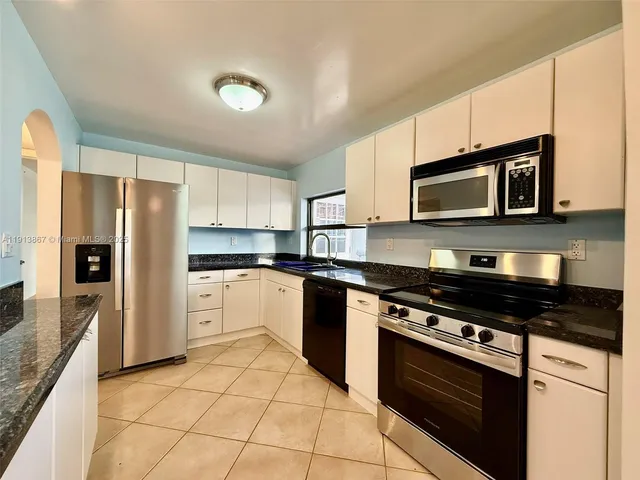 a kitchen with stainless steel appliances granite countertop a stove a refrigerator and a microwave