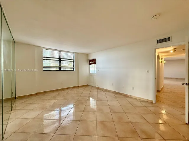 a view of empty room with kitchen and window