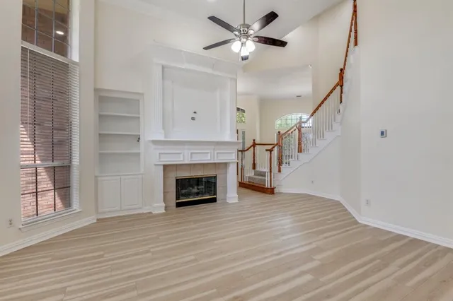 a view of an empty room with wooden floor fireplace and a window
