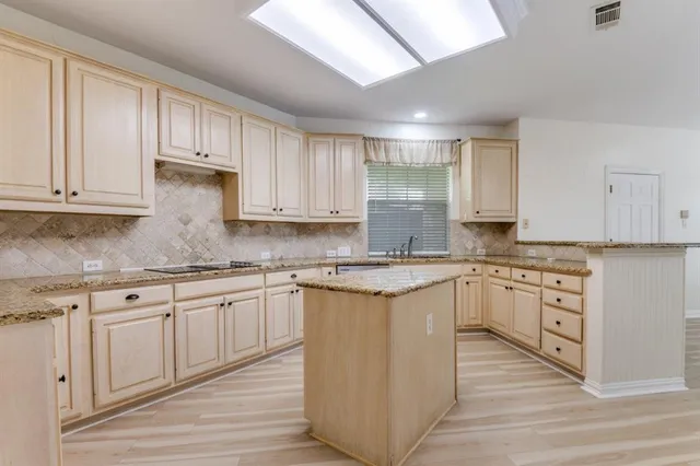 a kitchen with granite countertop a sink stove and white cabinets