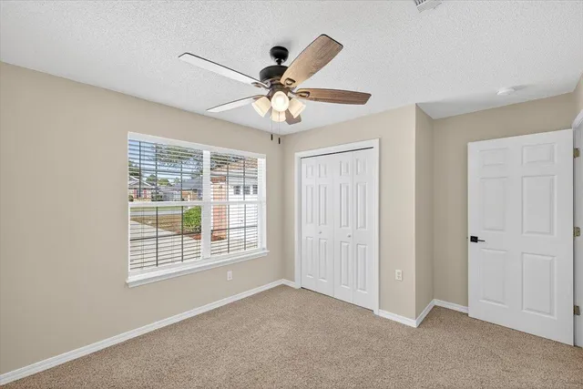 a view of an empty room with wooden floor and windows