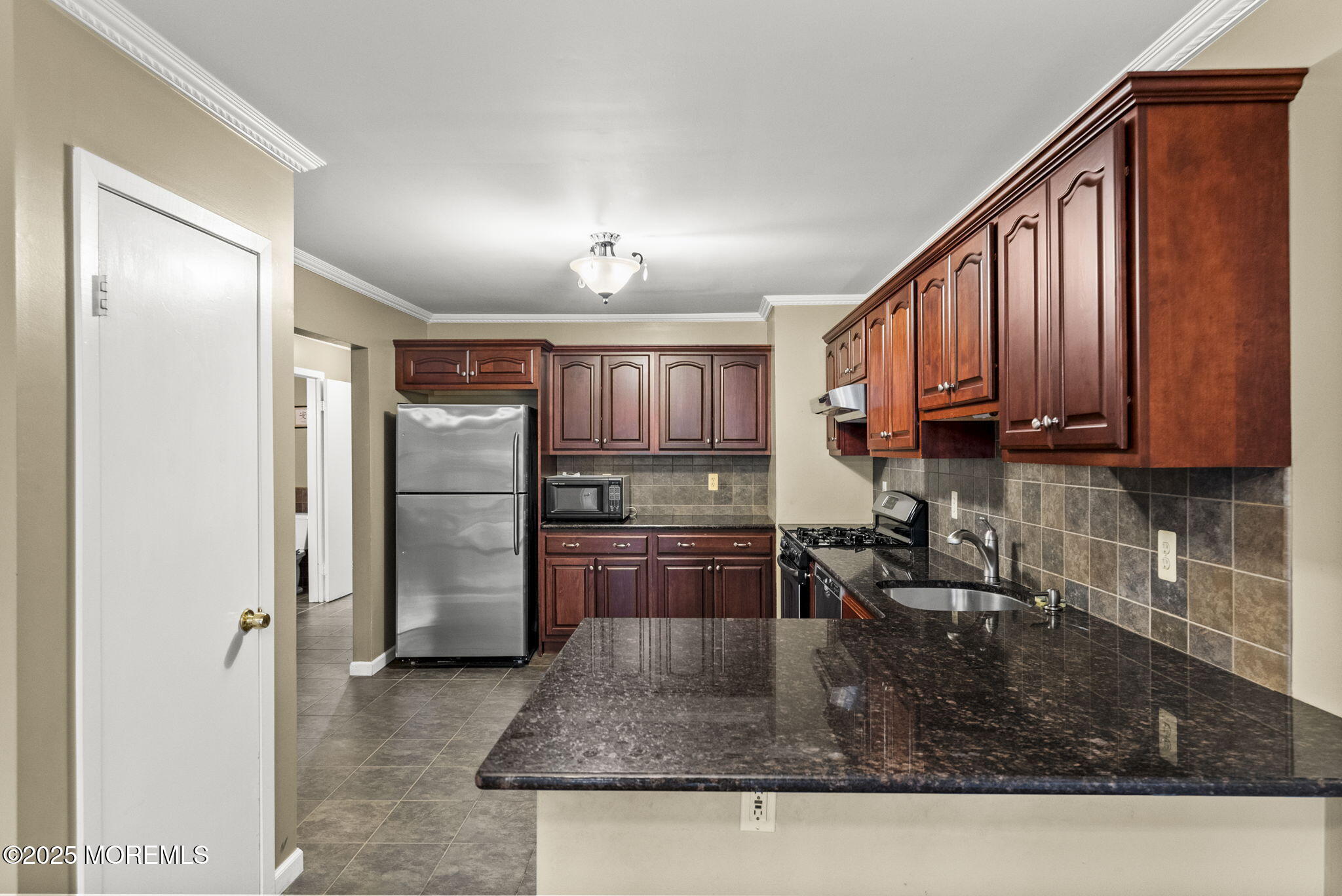 63 Atrium Way, Unit 63 Manalapan, NJ 07726 - Photo 8 of 40 a kitchen with stainless steel appliances granite countertop a refrigerator a stove and a sink with wooden cabinets