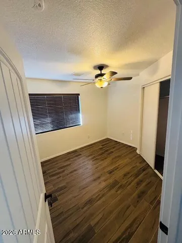 a view of an empty room with wooden floor and a ceiling fan