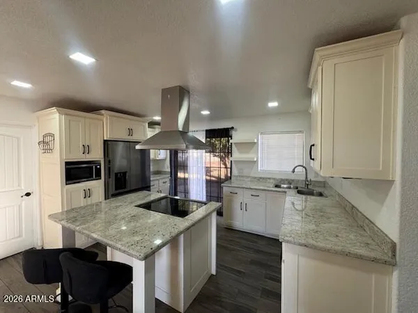 a kitchen with a stove center island cabinets and wooden floor