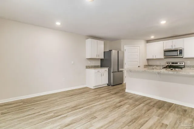 a kitchen with granite countertop a refrigerator and a stove top oven