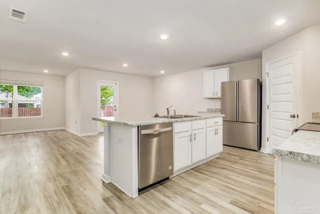a kitchen with a refrigerator a sink and wooden floor