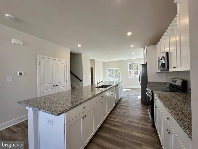 a kitchen with granite countertop a sink and a wooden floor