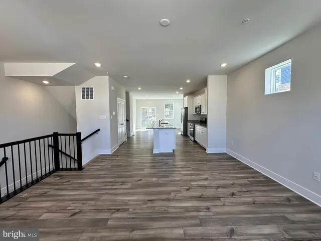 a kitchen with granite countertop a refrigerator a stove a sink and white cabinets with wooden floor