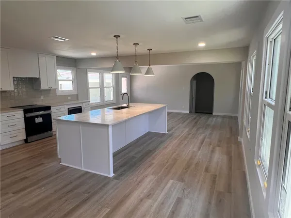 a large kitchen with stainless steel appliances granite countertop a stove and a wooden floors