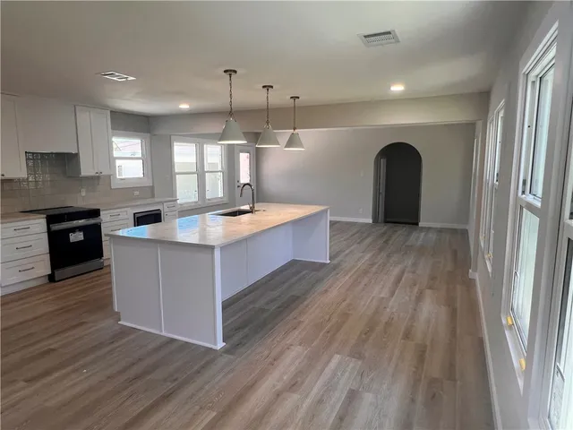 a large kitchen with stainless steel appliances granite countertop a stove and a wooden floors
